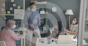 Boss Arab guy talking to diverse group of people employees wearing medical masks in office