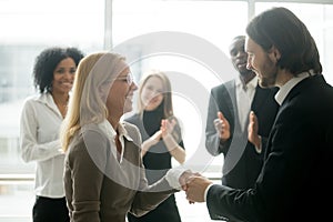 Boss handshaking rewarding female employee congratulating with p