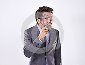 The boss has his eye on you. Studio shot of a young businessman against a white background looking through a magnifying