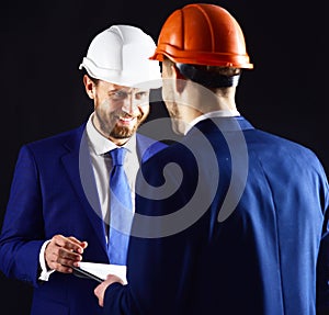 Boss in helmet gives instructions to employee.