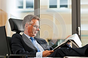 Boss in his office reading newspaper