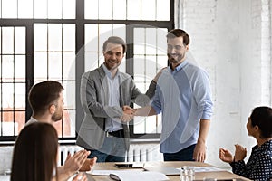 Boss introduces new employee to staff during briefing at boardroom