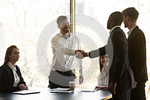 Boss shake hands with multi racial business partners starting negotiations