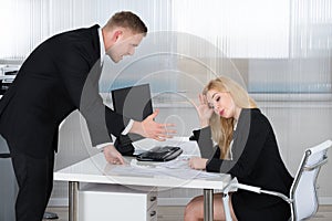 Boss Shouting At Employee Sitting At Desk