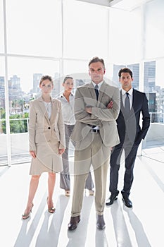 Boss standing with his arms folded with serious colleagues behind