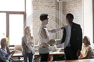 Boss thanking African American employee for good work, handshaking