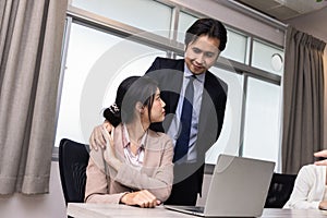 A Boss touching the shoulder of employee colleague in workplace at office