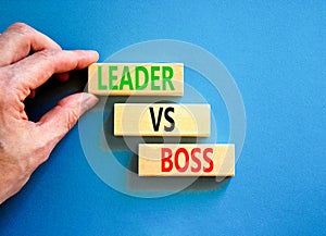 Boss vs leader symbol. Concept words Boss vs versus leader on wooden block. Beautiful blue table blue background. Businessman hand