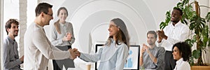 Boss handshaking with mixed race female employee congratulating with success photo
