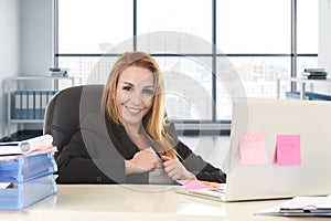 Bossy business woman with blond hair smiling confident leaning on office chair working at laptop computer