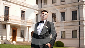 Bossy rich man in a suit and bow tie sits on leather sofa drinking glass of whiskey. Confident imperious groom posing on