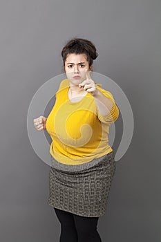 Bossy 20s fat woman showing her index and fist to denounce photo