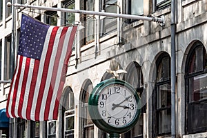 Boston, MA USA - Shopping Mall Store front with american flag waving with a big clock beside it