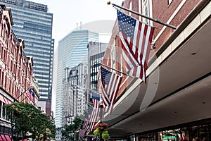 Boston, MA USA Shopping Mall Store front with american flags waving with skyscrapers in the background skyline