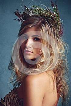 Botanical beauty. a young woman posing with flowers in her hair against a blue background.