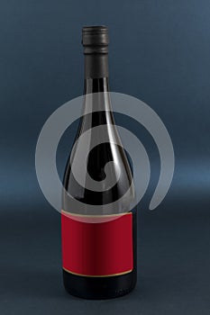 Botella de vino con etiqueta roja para texto o marca, y un fondo de color azul photo