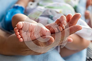 Both feet of a newborn baby child and female hand