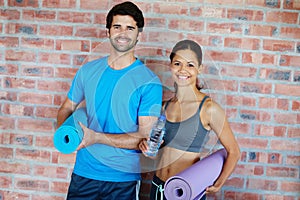 We are both fitness fanatics -Fitness Couple. Portrait of a gym going couple who are both holding gym mats.