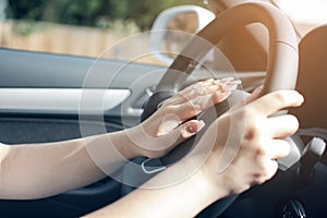 Both hands of woman gripping wheel driving left hand drive car,