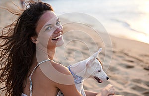 We both love the beach. an attractive young woman enjoying the beach with her dog.