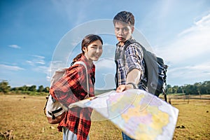 Both male and female tourists carry a backpack standing on the lawn