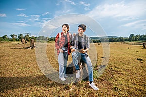 Both male and female tourists carry a backpack standing on the lawn. And look to the side