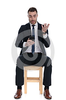 Bothered businessman texting on phone and gesturing photo