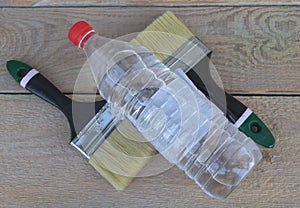 A bottle of acetone - two paintbrushes and gloves in the background - wooden background - Construction concept