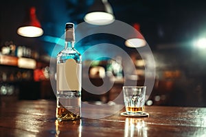 Bottle of alcohol and glass on bar counter closeup