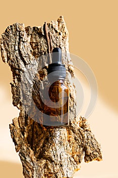 Bottle of amber glass with cosmetic serum on brown background. Mockup of container with dropper lid with collagen in