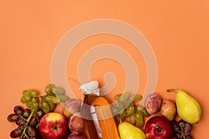 Bottle With Apple Cider or Vinegar with Raw Autumn Fruits on Orange Background Top View Copy Space