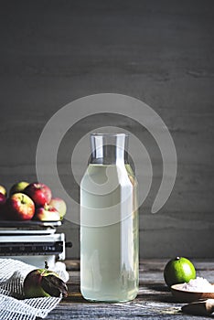Bottle of apple cider vinegar on rustic background