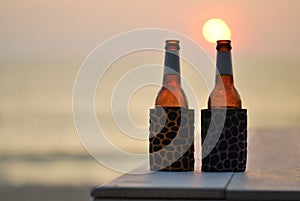 Bottle of beer on the beach at sunset
