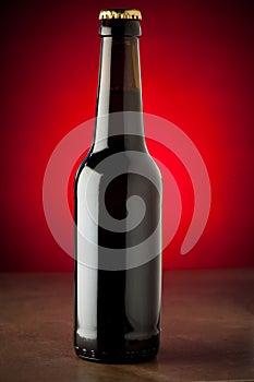 Bottle of beer on a stone table over red background