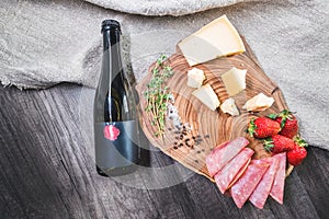A bottle of beer and a variety of snacks on a wooden tray stand on the table. The concept of food and snacks, table