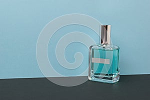 A bottle with blue perfume on a black and blue background