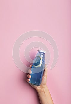 A bottle of blue water or detox drink in a woman`s hand