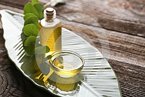 Bottle and bowl with eucalyptus essential oil on wooden table