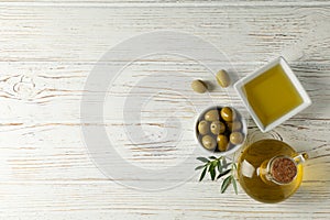 Bottle and bowl with olive oil, bowl with olives on wooden background