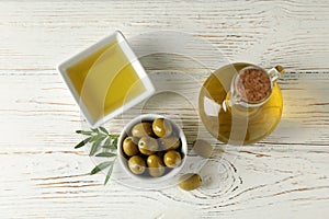 Bottle and bowl with olive oil, bowl with olives on background, top view