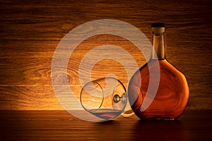 Bottle of brandy with wine glass on wooden background