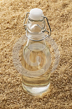 Bottle with brown rice vinegar standing in brown rice full frame