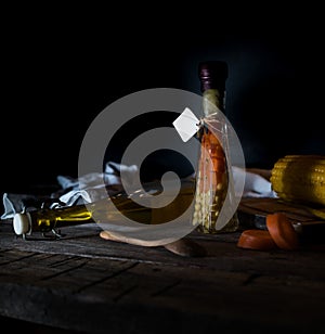 Bottle of canned carrots and corn, spices on a wooden table. Dark background