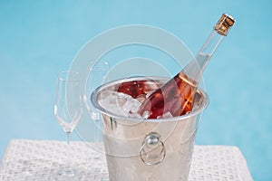 bottle of champagne in bucket with ice and two empty glasses