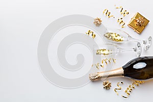 Bottle of champagne with colored glitter, confetti and gift box space for text on colorfull background, top view