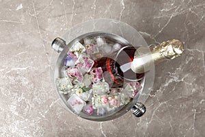 Bottle of champagne with floral ice cubes in bucket on table