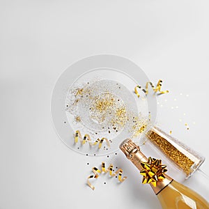 Bottle of champagne, glass with gold glitter and space for text on white background. Hilarious celebration