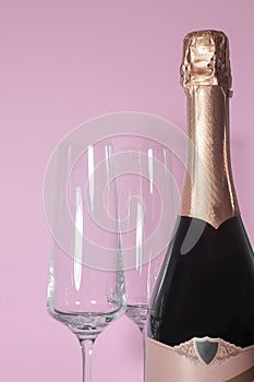 Bottle of champagne with glasses on a pink background