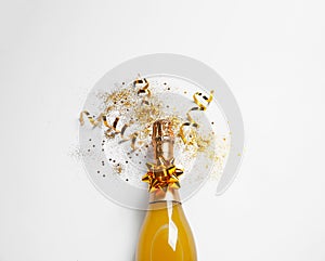 Bottle of champagne with gold glitter and bow on white background, top view. Hilarious