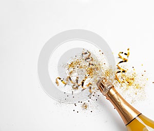 Bottle of champagne with gold glitter, confetti on white background, top view. Hilarious celebration